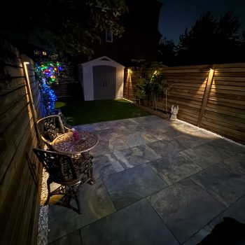 A picture of a finished garden transformation at night with pretty garden lights