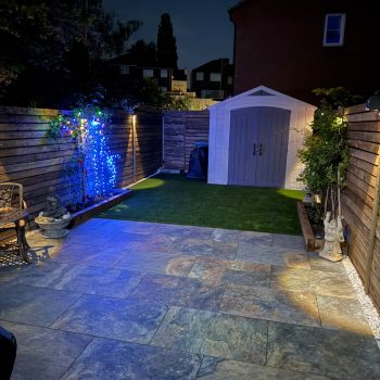 A picture of a finished garden transformation at night with pretty garden lights